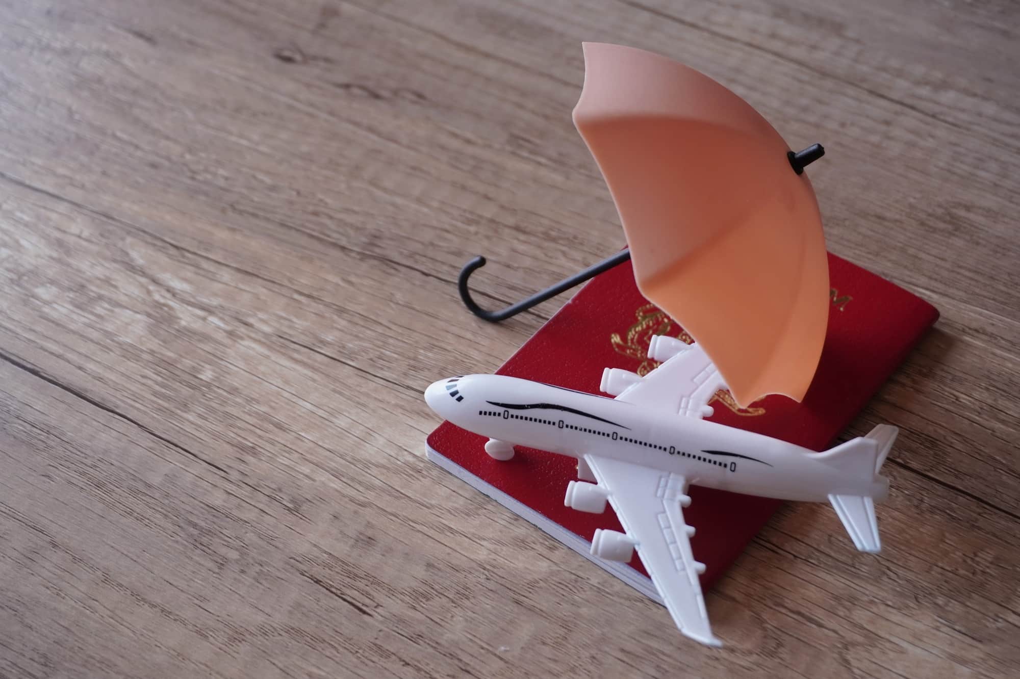 Closeup image of toy plane, passport and umbrella on table with copy space.